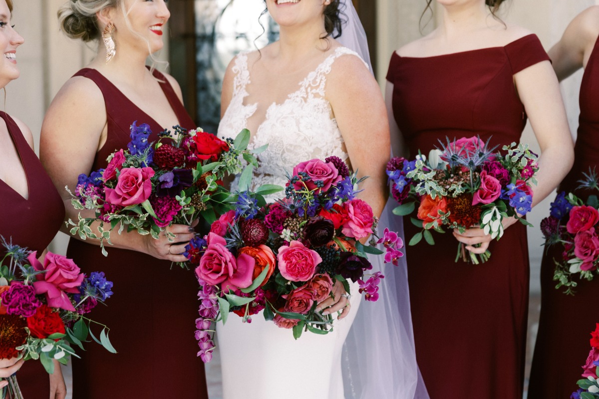 Close-up of bouquets being held by bride and bridesmaids in maroon dresses