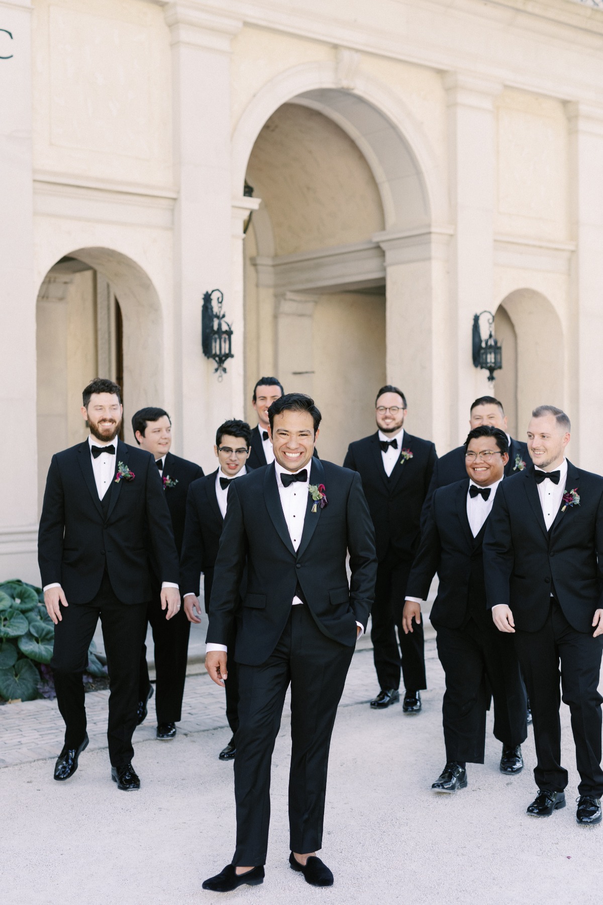 Groom and groomsmen walking toward camera in black suits with black bowties