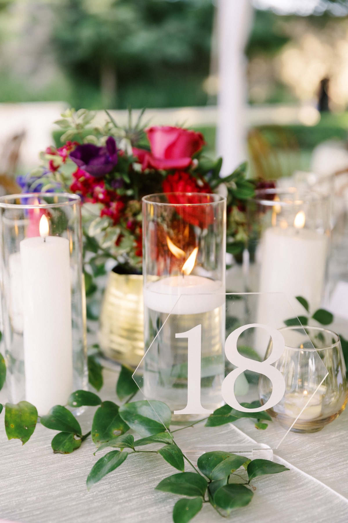 Table number with floral arrangement and floating candles in clear vases