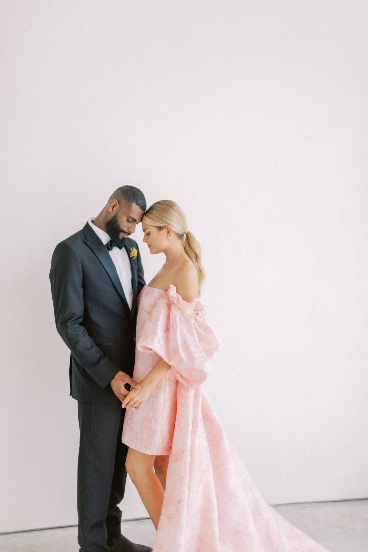 Groom and bride face to face with bride in pink off the shoulder dress