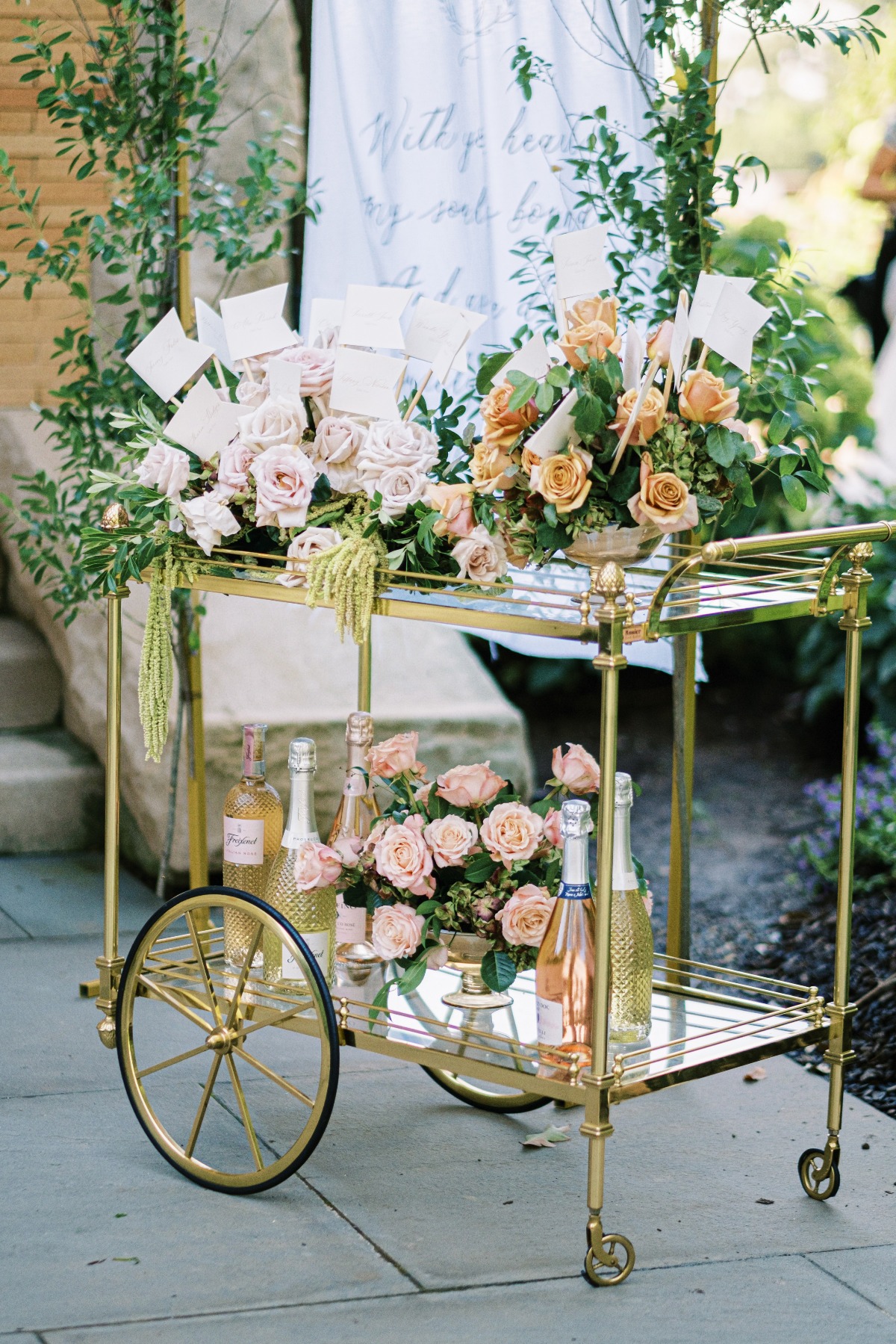 Bar cart with floral arrangements, seating assignment flags and French rose wine