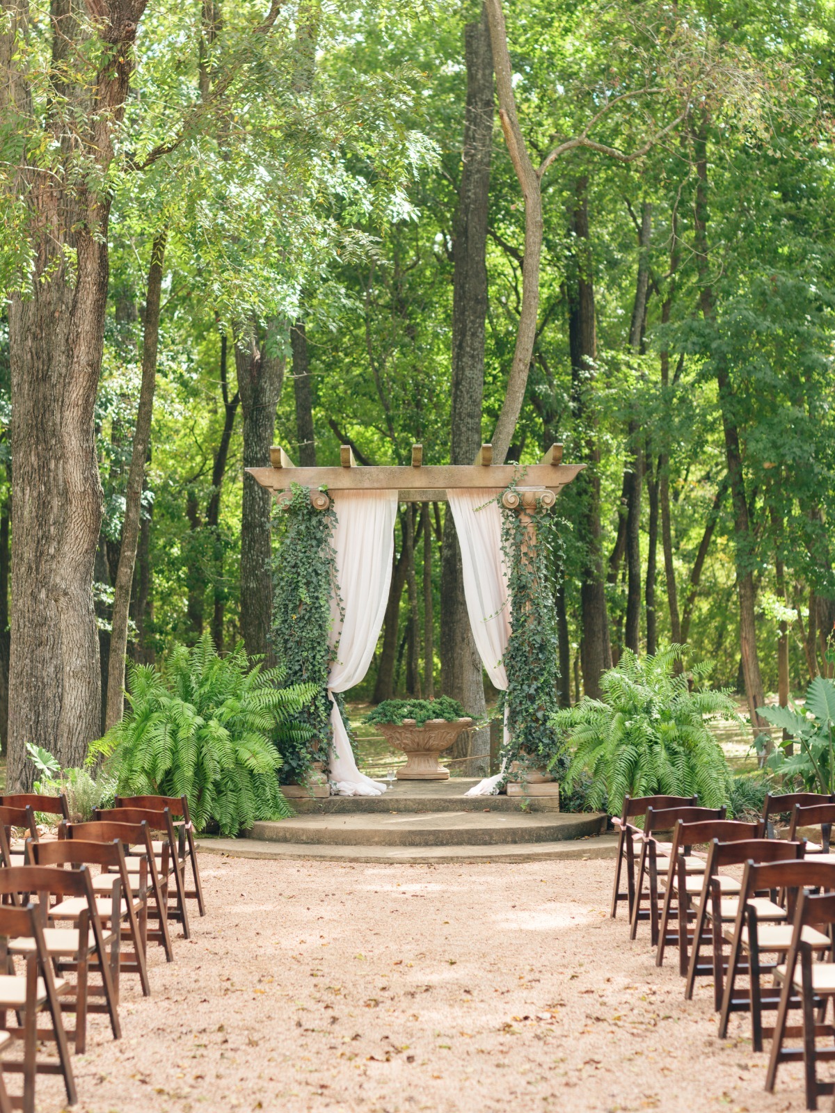 Outdoor wedding venue with pergola and wood chairs