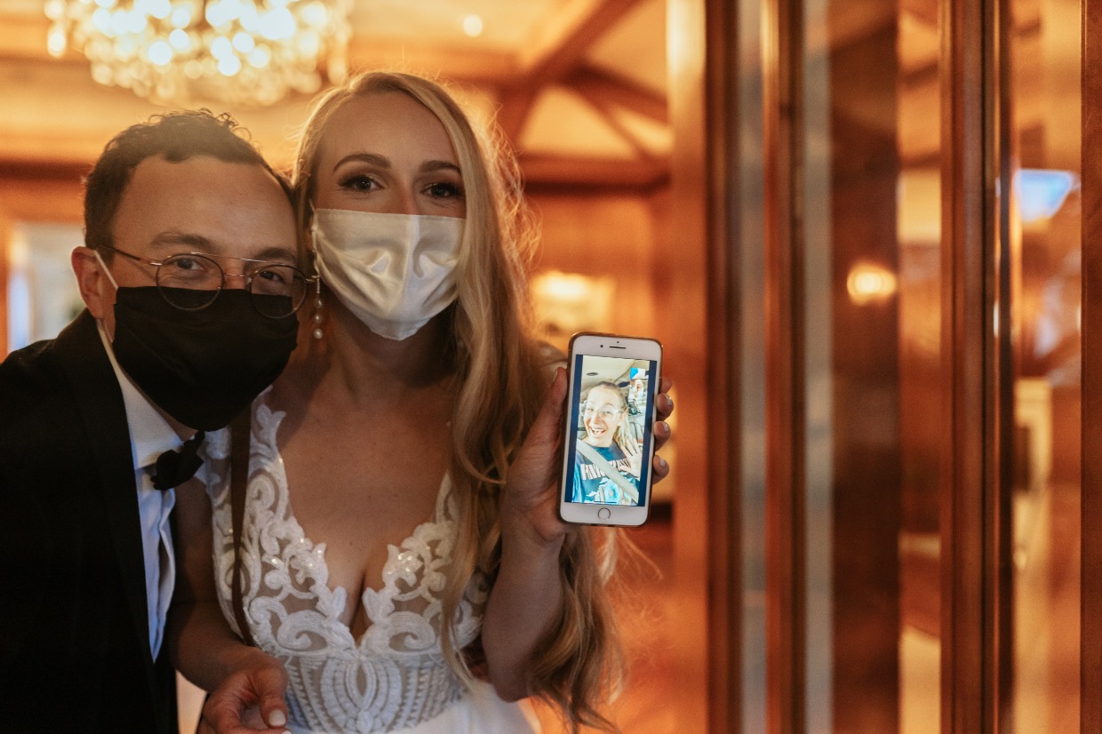 Bride and groom wearing masks video calling wedding guest