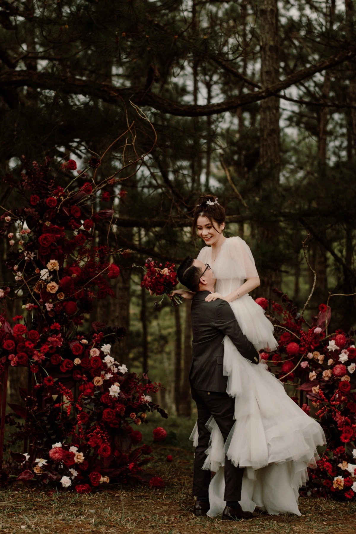 red floral wedding arch in woods