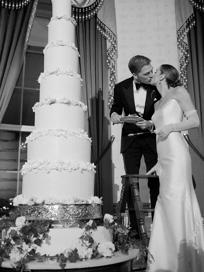 Naomi Biden cutting wedding cake in reception dress and gloves