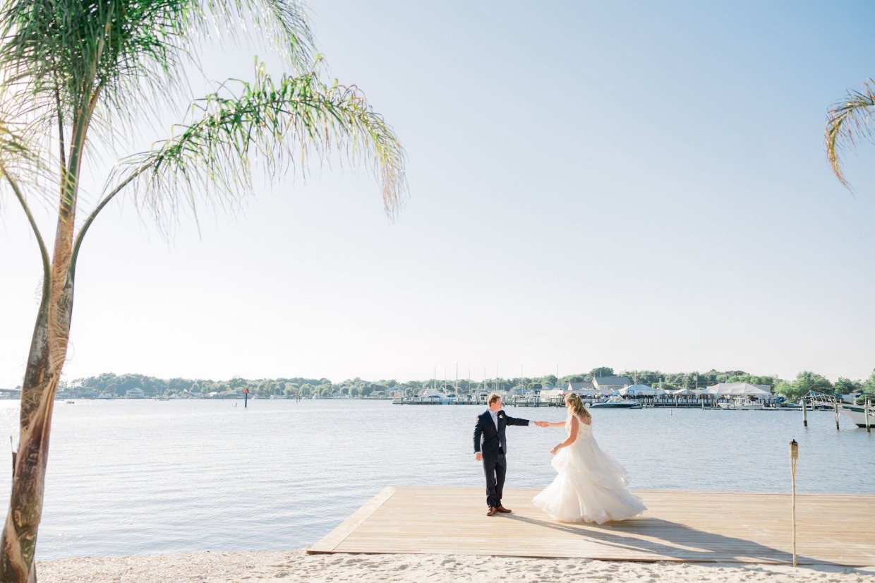 Tropical wedding with couple dancing on pier at sunset