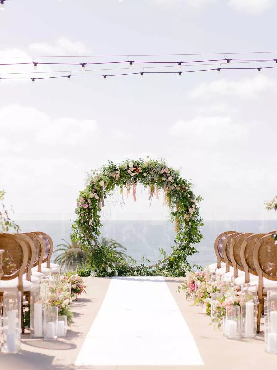 Outdoor wedding aisle with floral circle arch and ocean view
