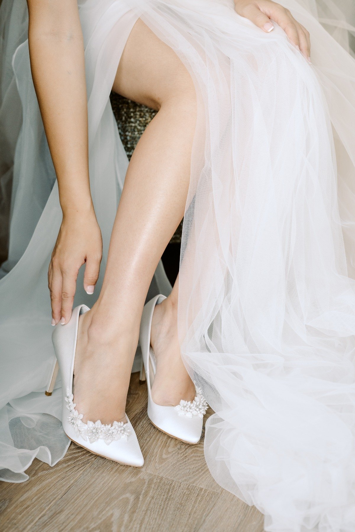 bride putting on her shoes in tulle and organza gown