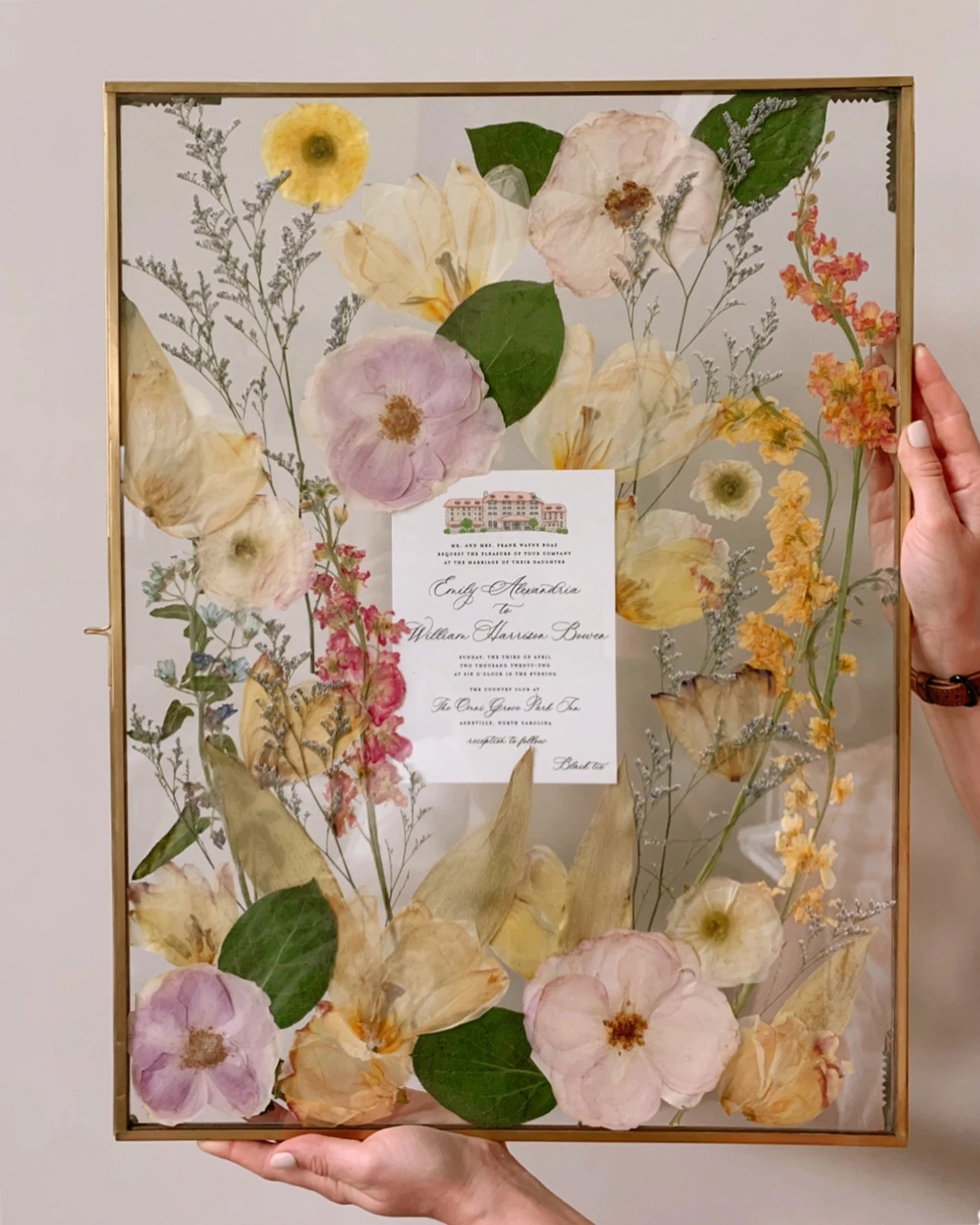 pressed flowers in the frame with wedding invitation