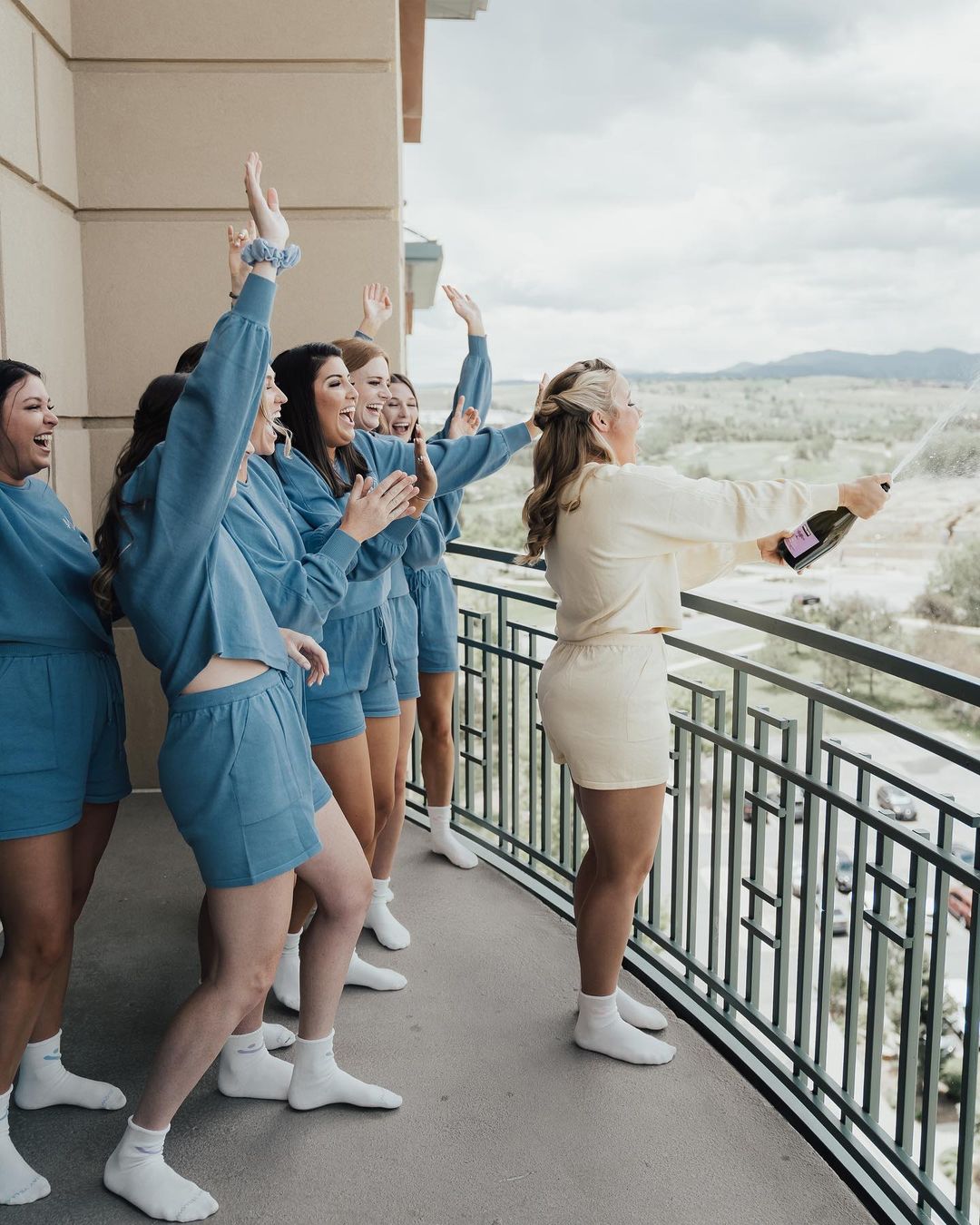 bridesmaids popping champagne in matching sweat sets