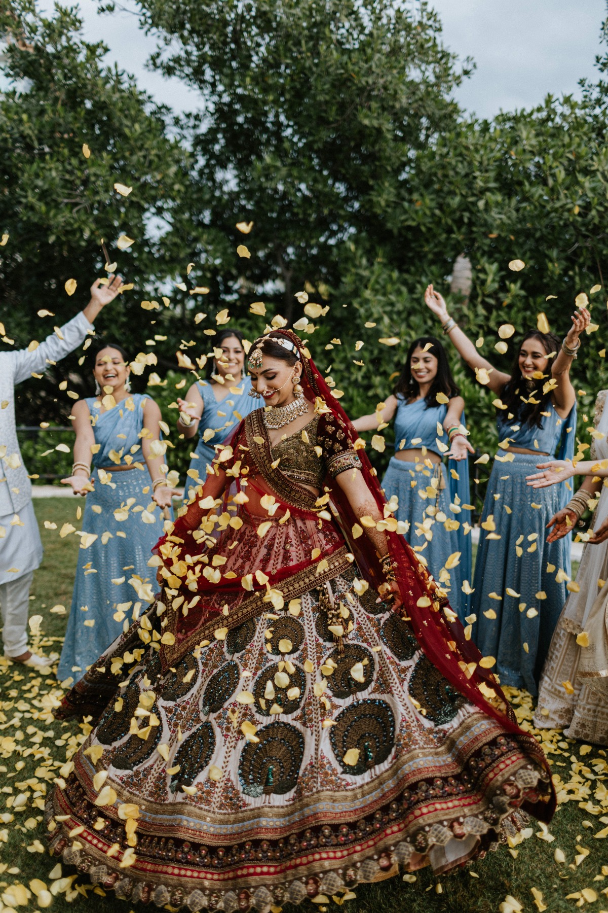 Indian bride in red and gold sari being showered with yellow petals