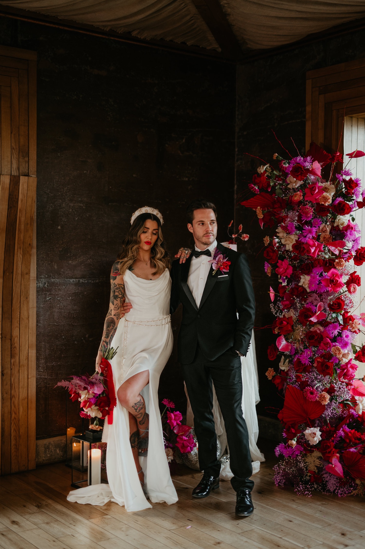 bride and groom at pink and red wedding with floral arch