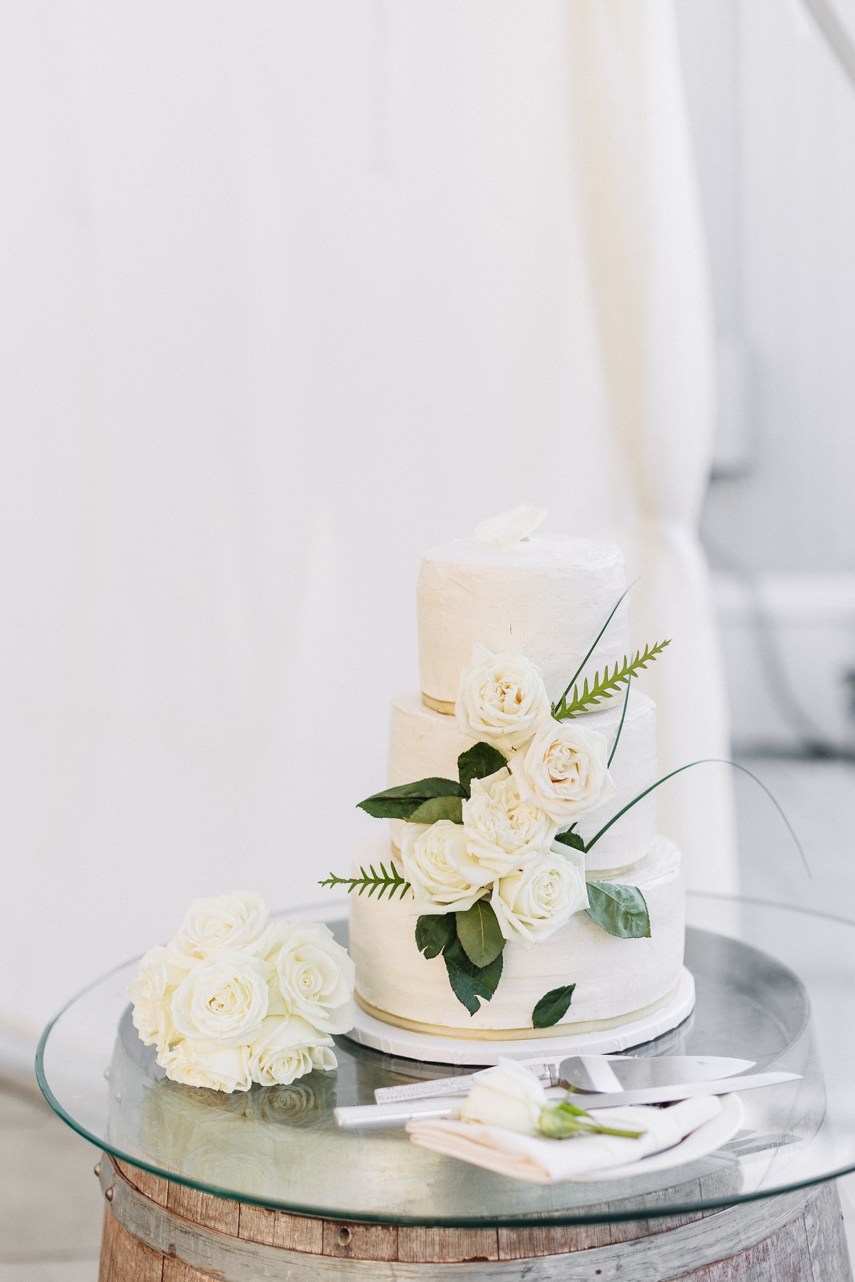 buttercream frosted three tiered wedding cake with fresh roses