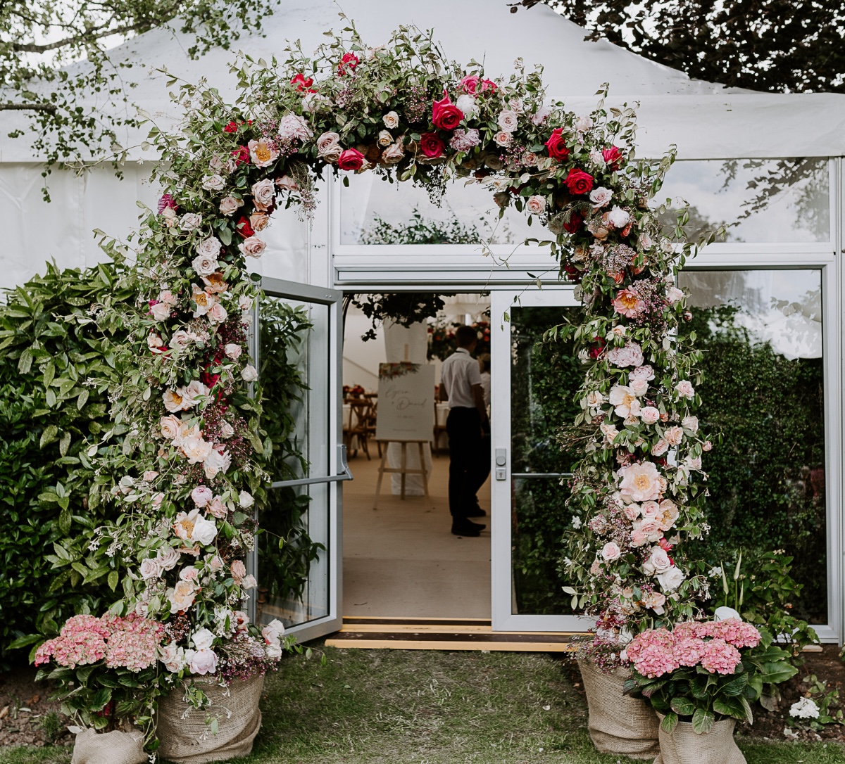 red white pink floral arch at tented reception