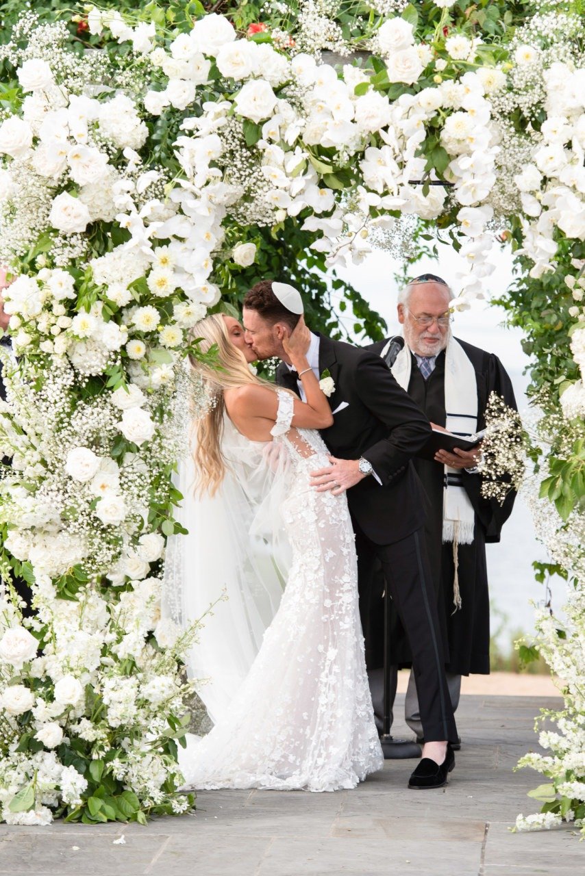 first kiss wedding ceremony with white floral arch