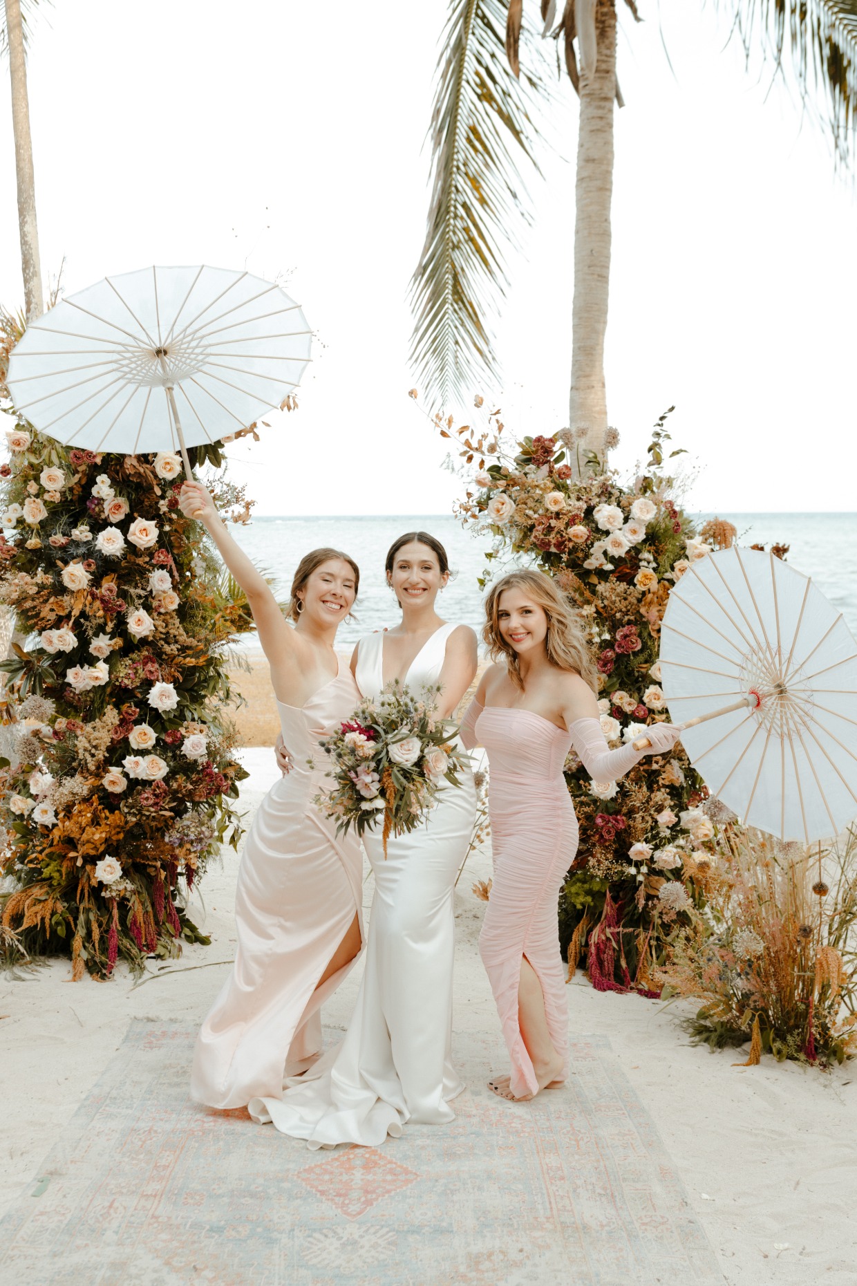 S.O.S. Planners beach wedding with blush florals, bridesmaids, and parasols