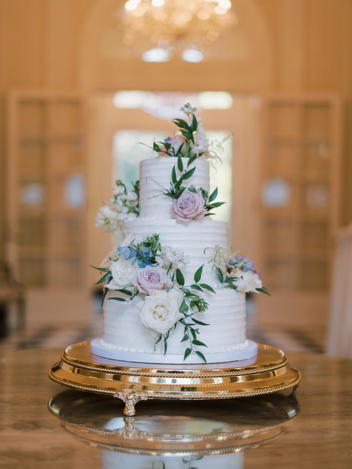 white cake on gold stand adorned with florals