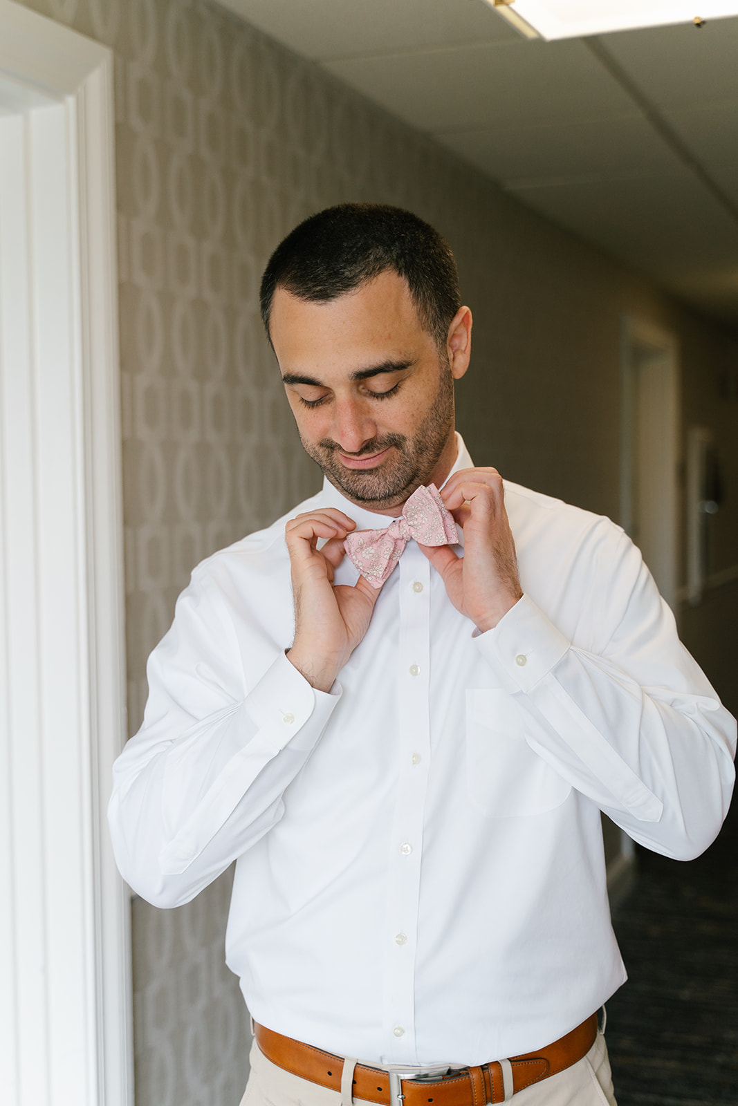 Groom getting ready with pink tie 