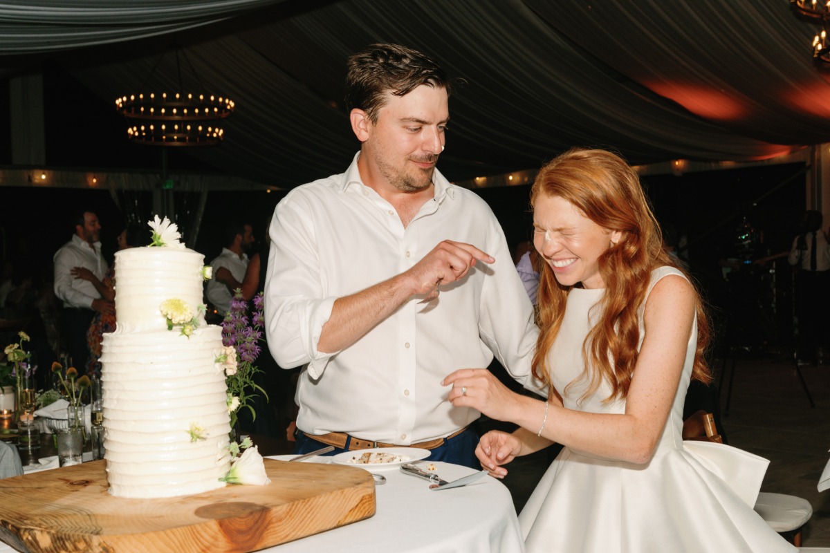 Playful cake cutting at tented reception 