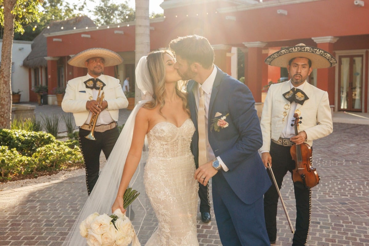 Bride and groom kiss by mariachis