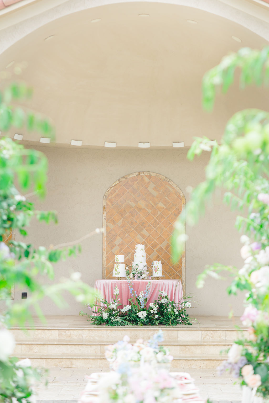 Three pastel wedding cakes on pink stand 