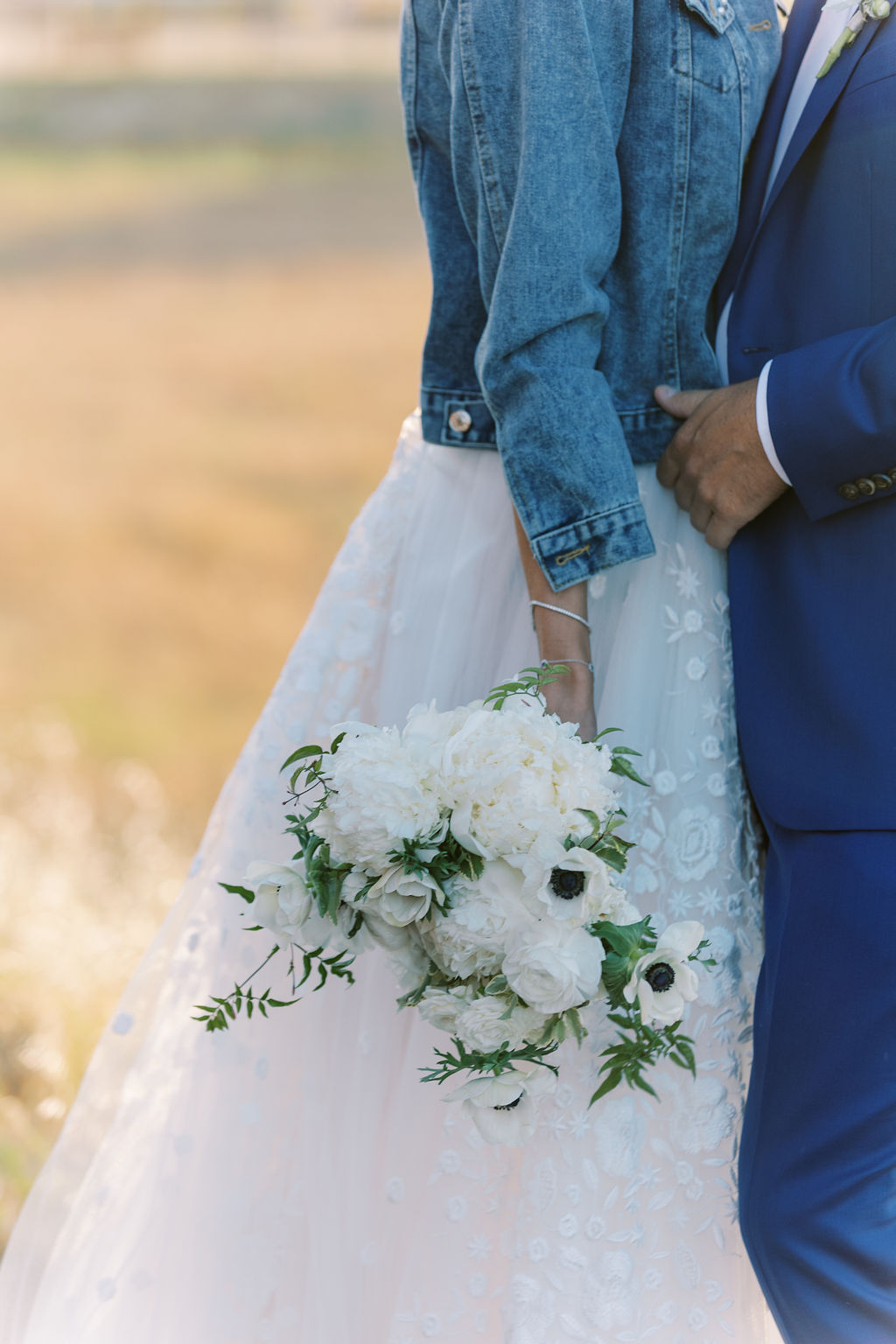 Bride in jean jacket holding bouquet 