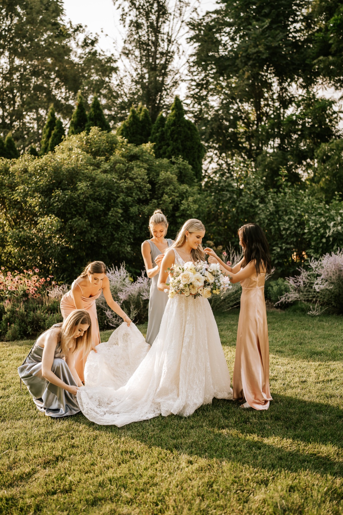 Bridemaids helping bride into lace gown