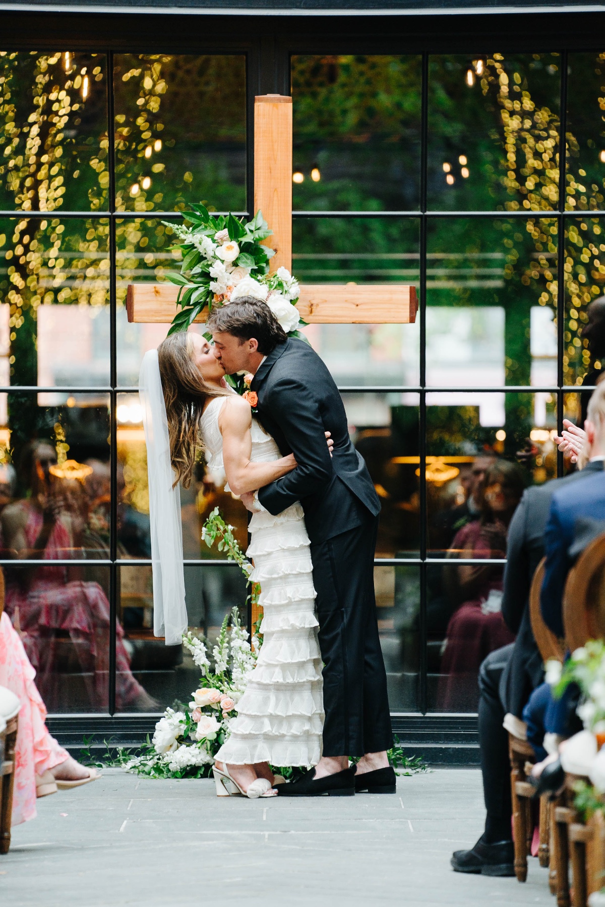 first kiss in front of cross backdrop wedding ceremony