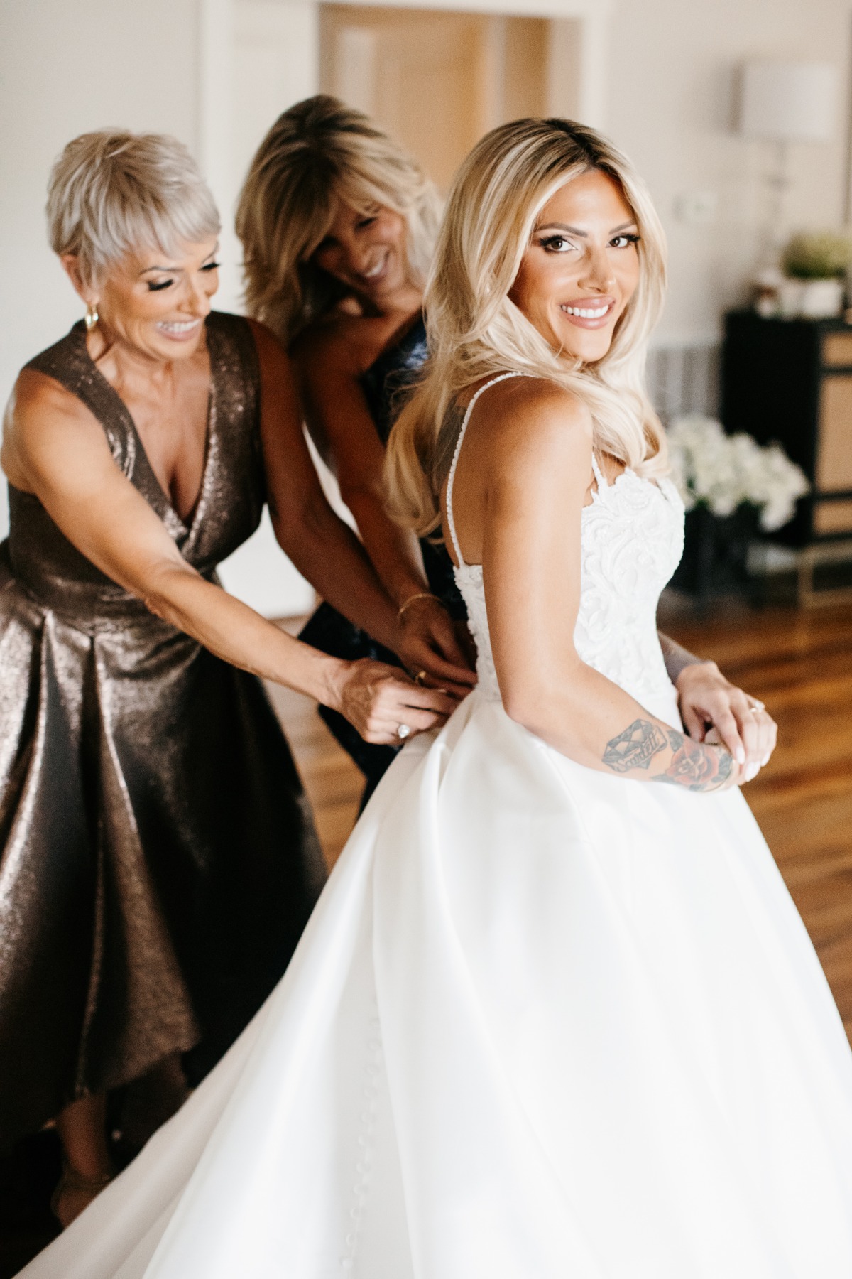 moms zipping wedding dress for blonde bride