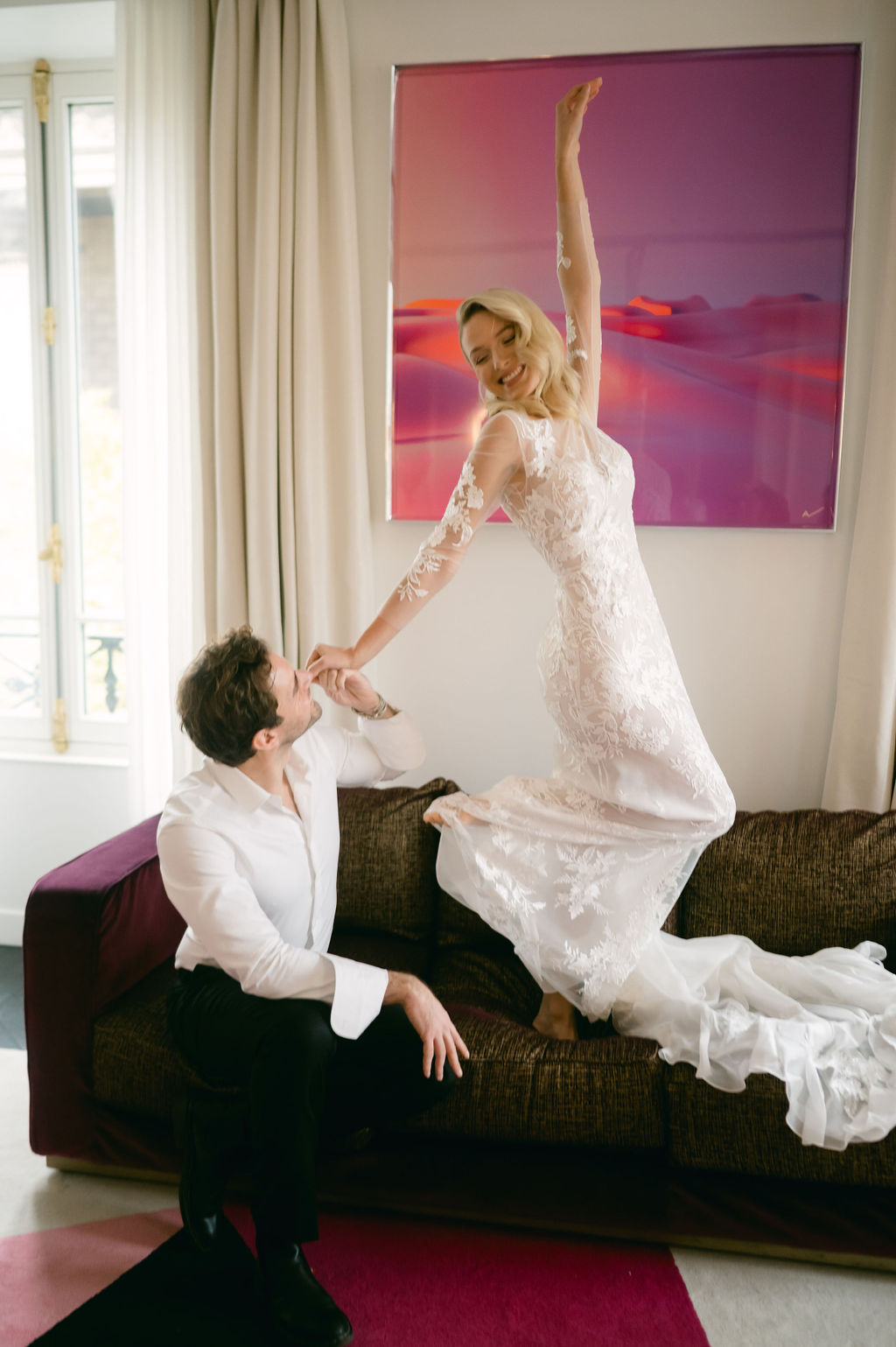 Bride dancing on couch in Paris hotel room 