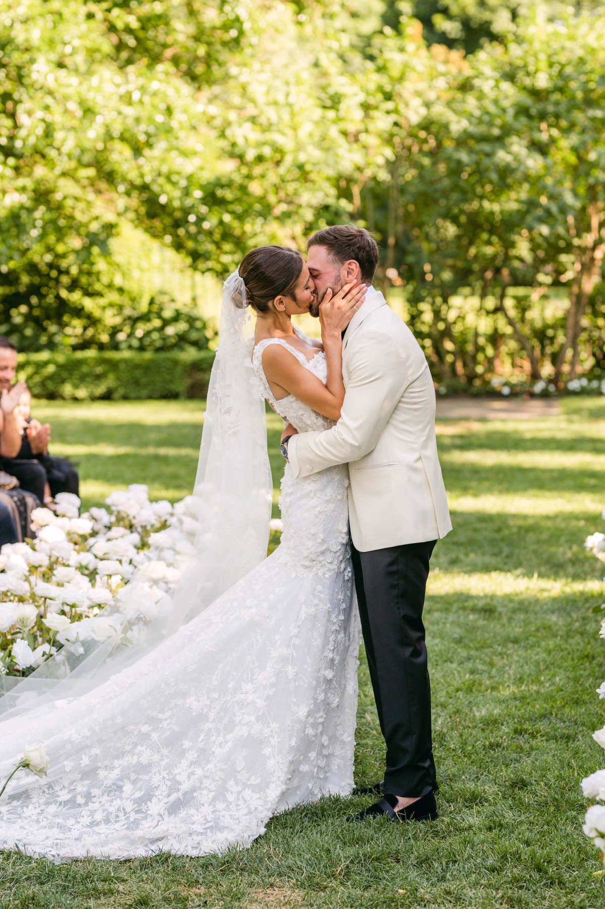 First kiss at white floral outdoor wedding ceremony 