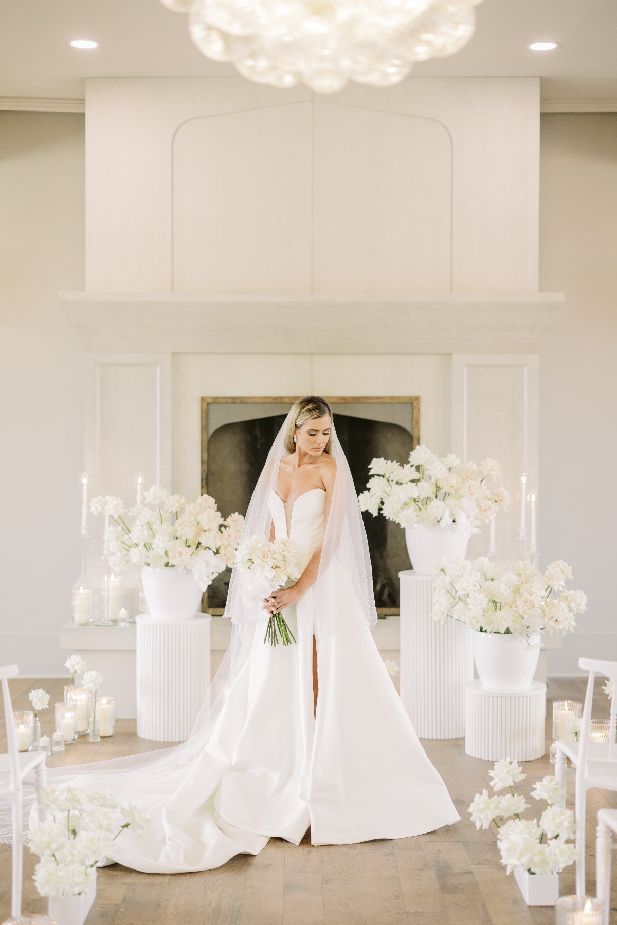 Elegant bride at white floral wedding ceremony in front of fireplace