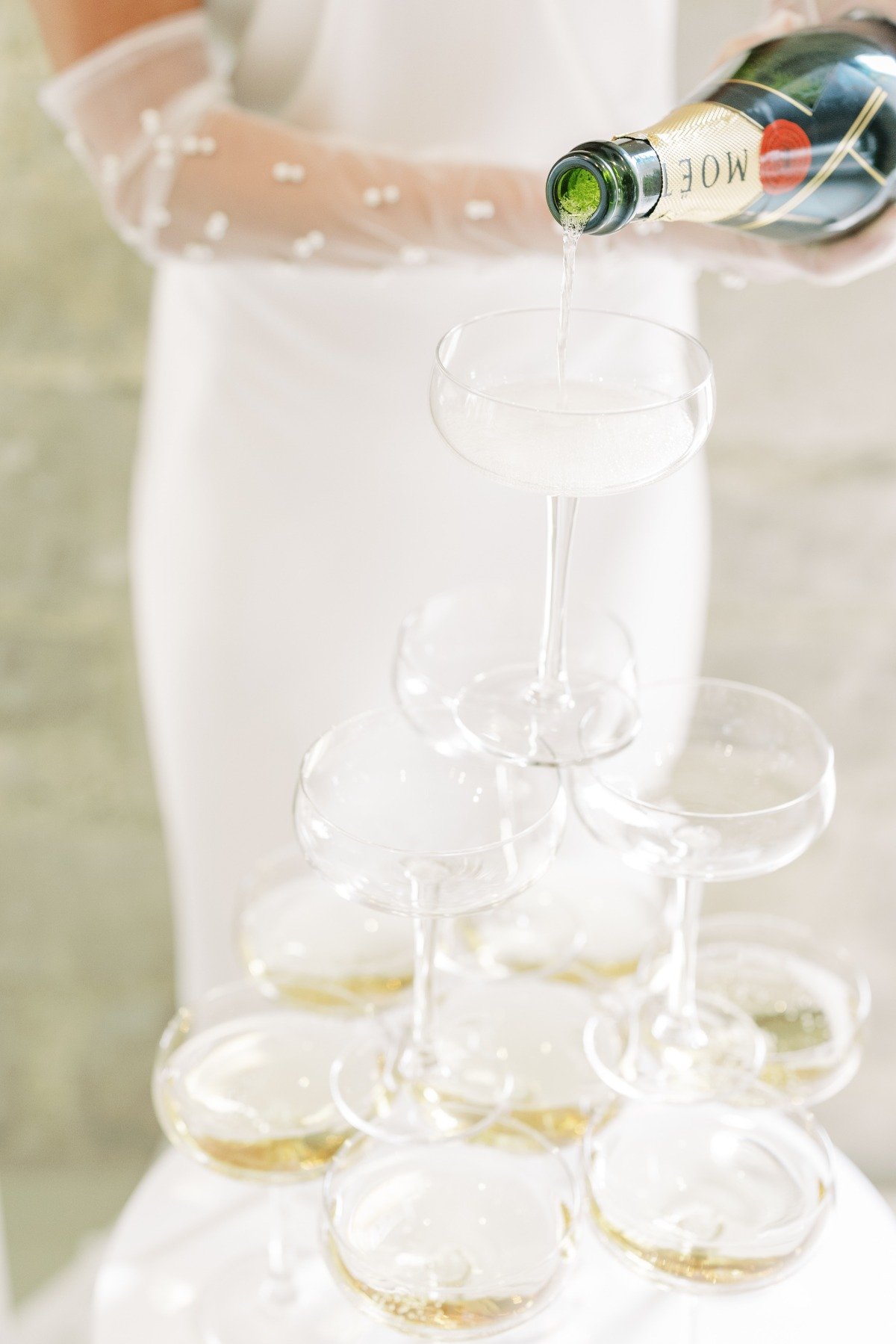 Bride with pearl gloves pouring a champagne tower