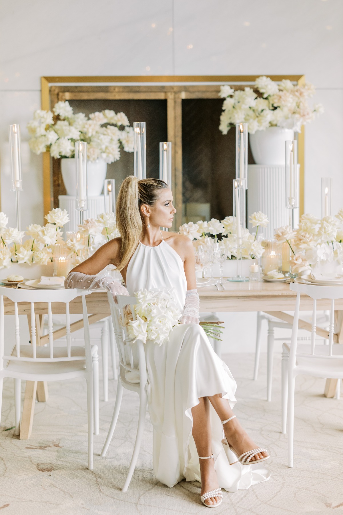 Modern bride sitting at elegant white reception table 