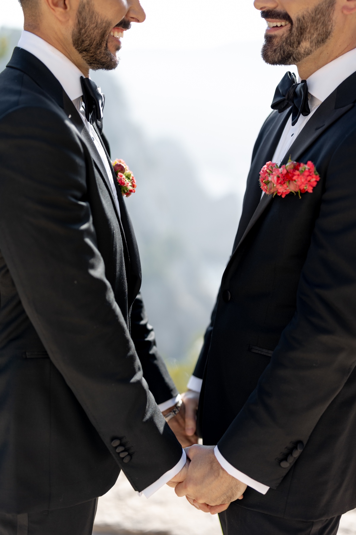 Matching coral colorful wedding boutonnieres for two grooms 