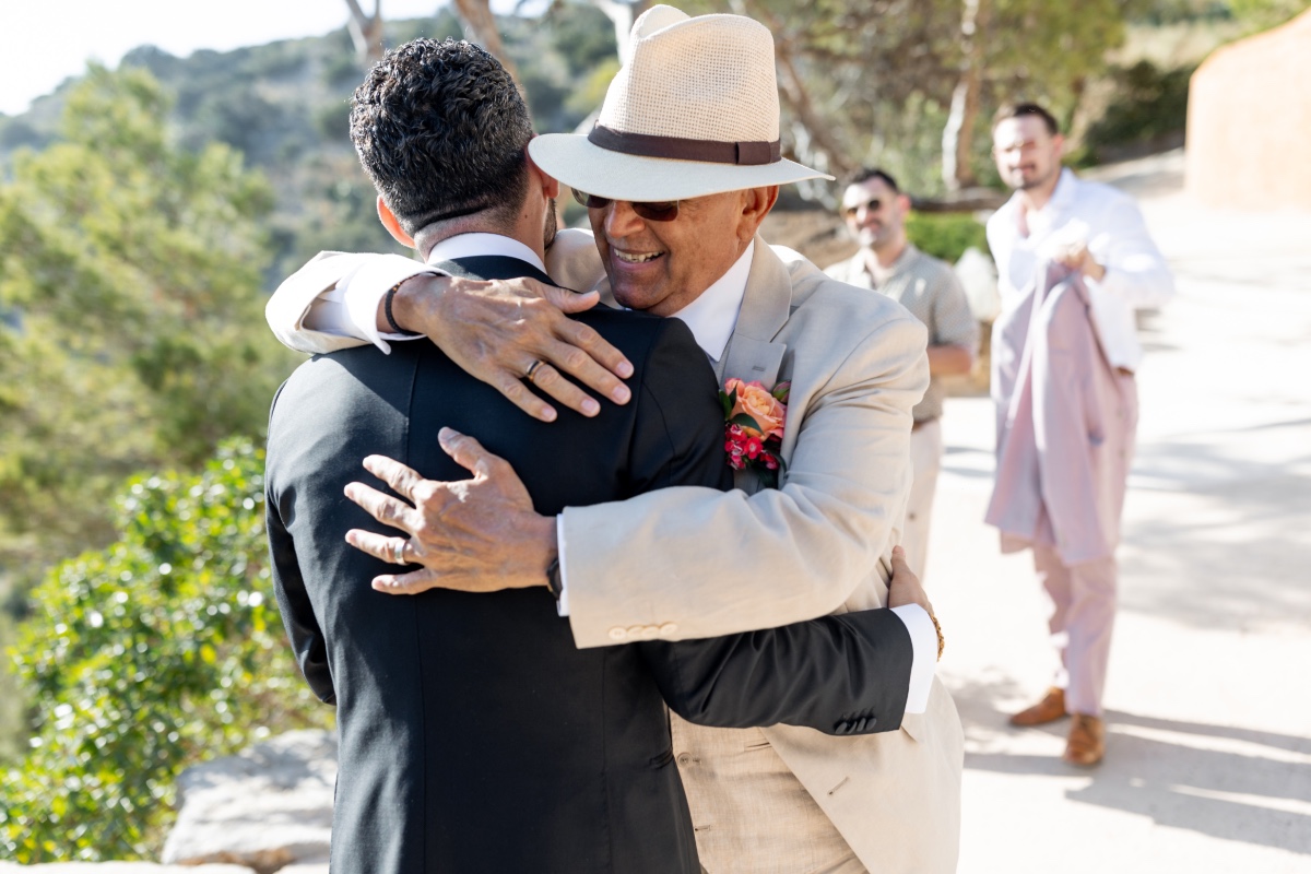 Father of the groom hugging groom after wedding ceremony 
