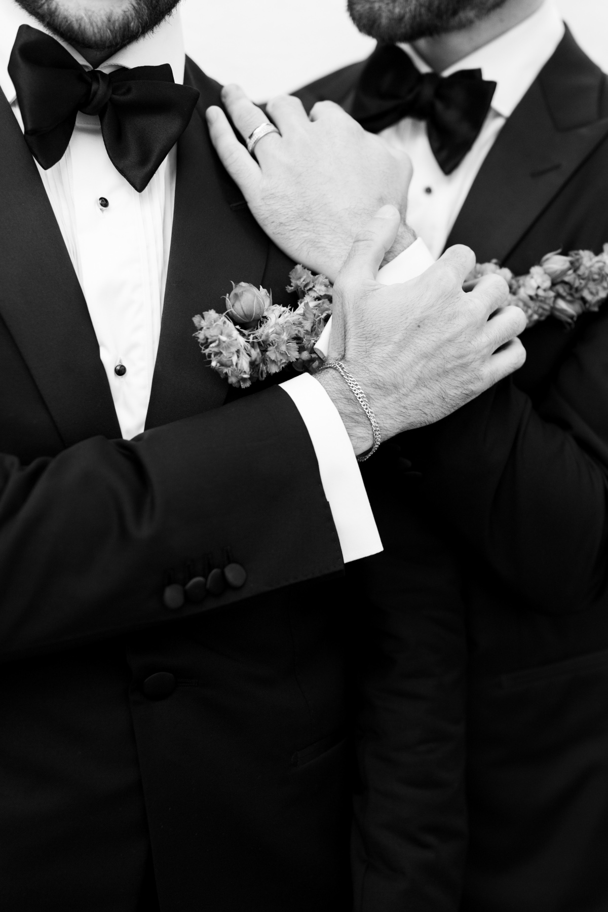 Fashionable grooms in black tuxedos and gold accessories 