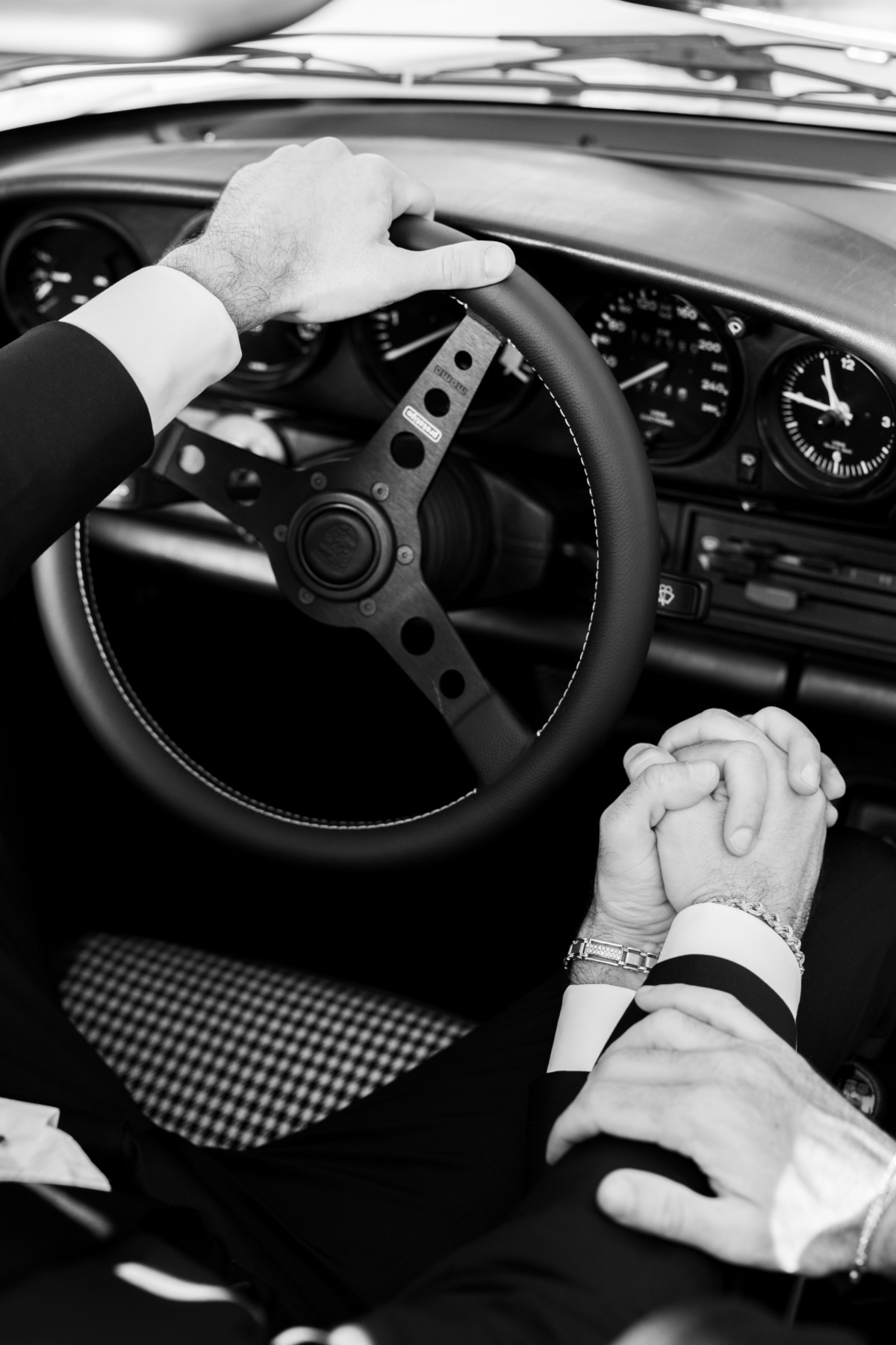 Two grooms holding hands in sporty vintage Porsche 