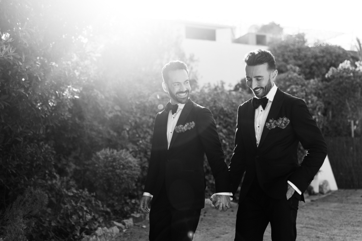 Two handsome and stylish grooms walking from ceremony 