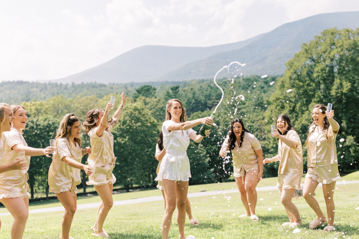 Bride and bridesmaids popping champagne wearing matching pjs