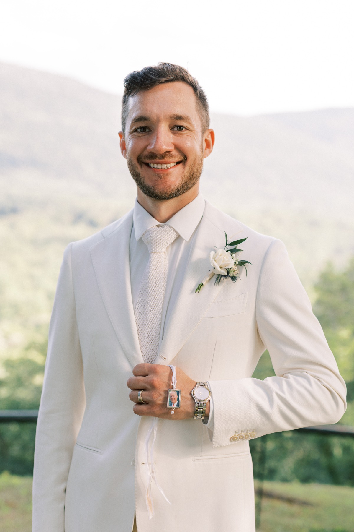 Groom in off-white suit from Suit Supply carrying locket 