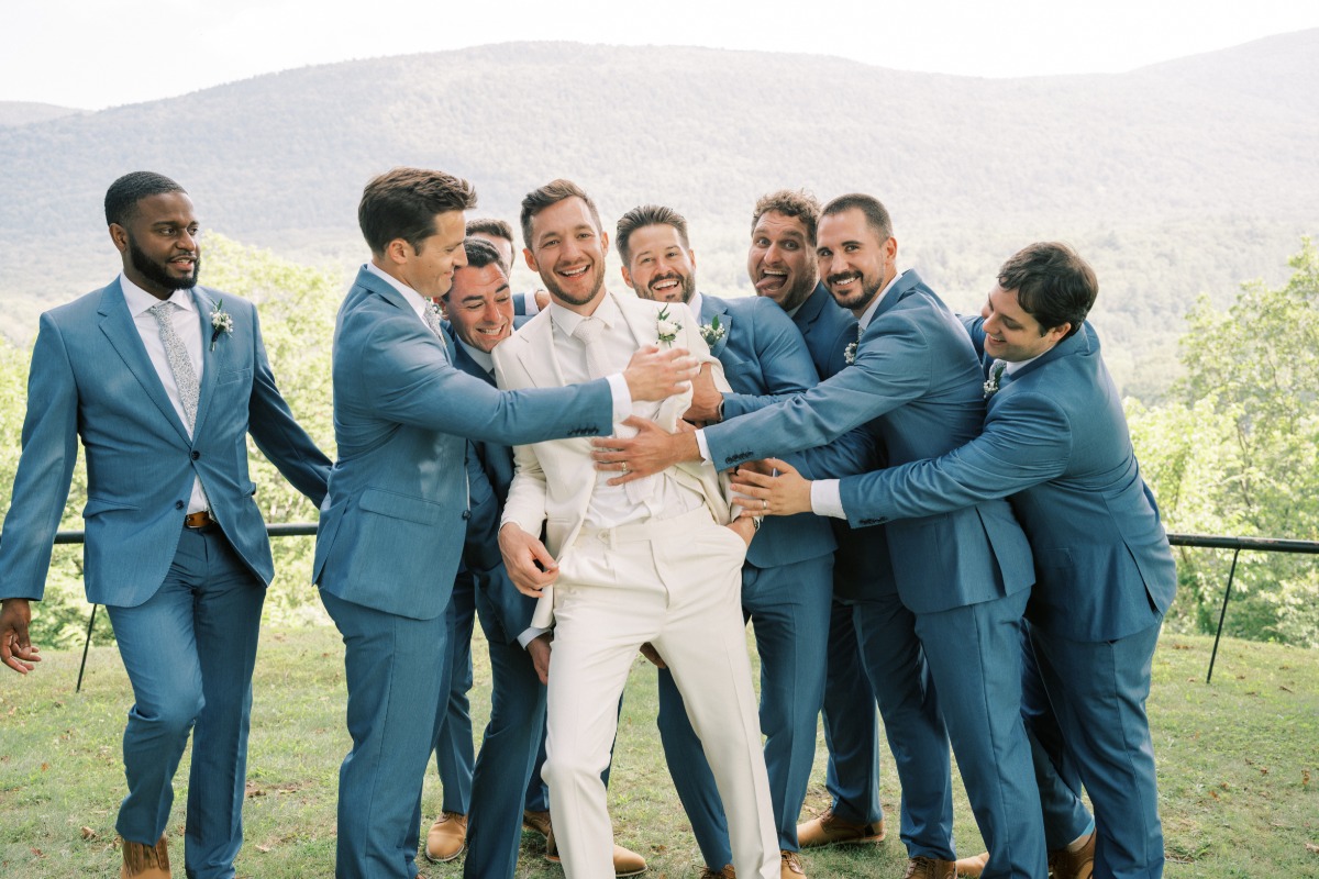 Groom in white suit with groomsmen in modern blue suits 