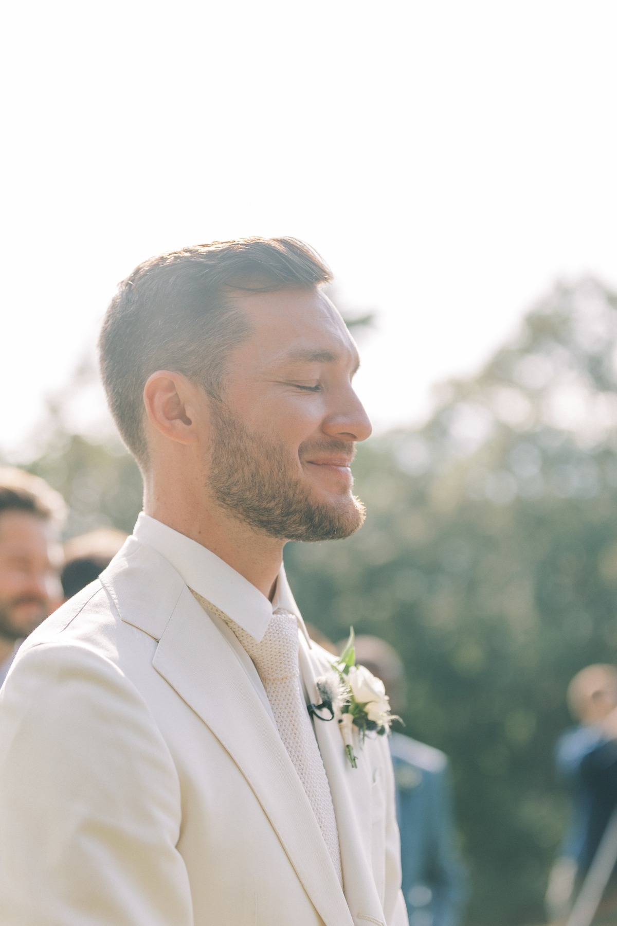 Emotional groom seeing bride walk down the aisle at garden wedding