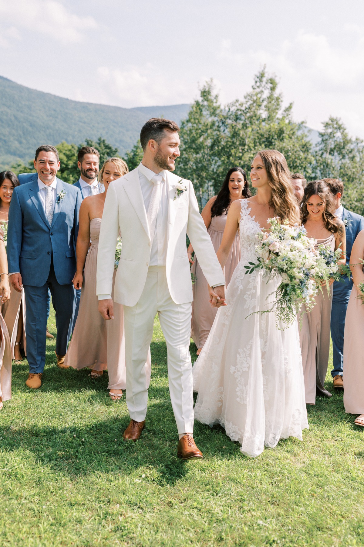 Elegant Vermont bride and groom walking with blue bridal party