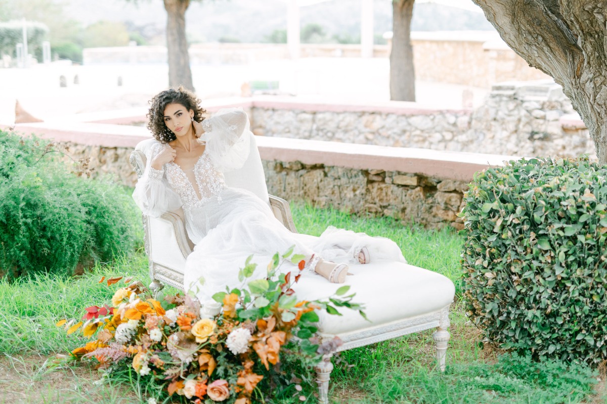 Bride lounging in dreamy white chaise lounge with florals 