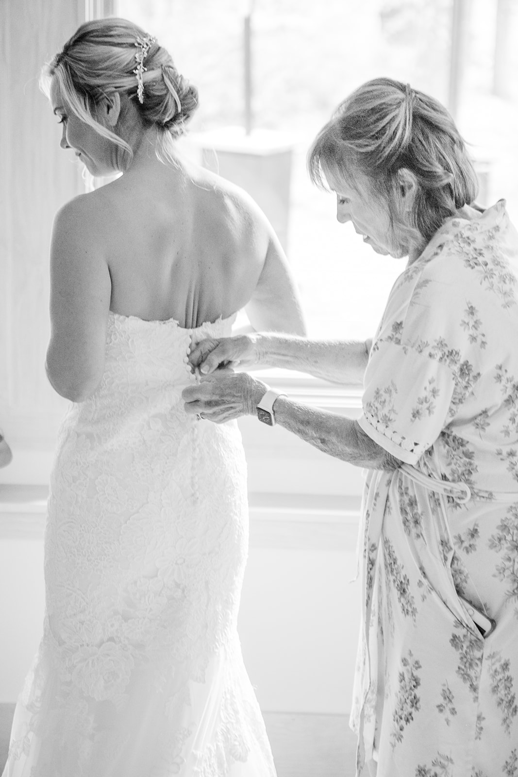 mom zipping up bride in wedding dress