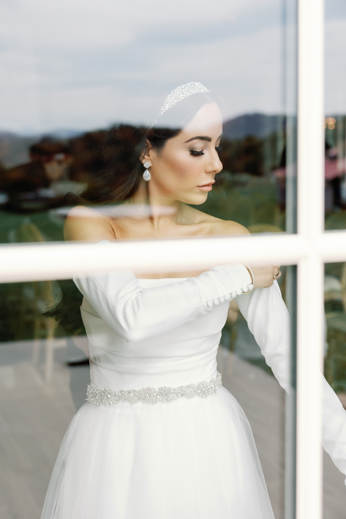 Glamorous bride putting on detached wedding dress sleeves