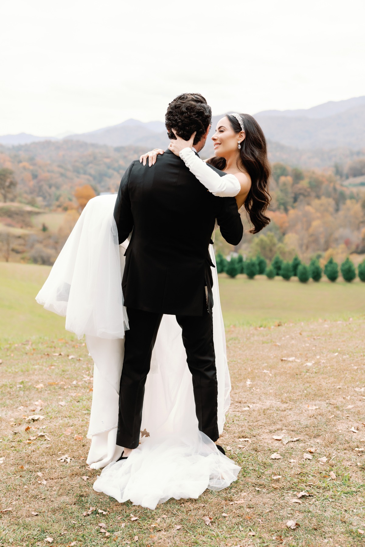 Groom carrying bride at dreamy outdoor fall wedding 