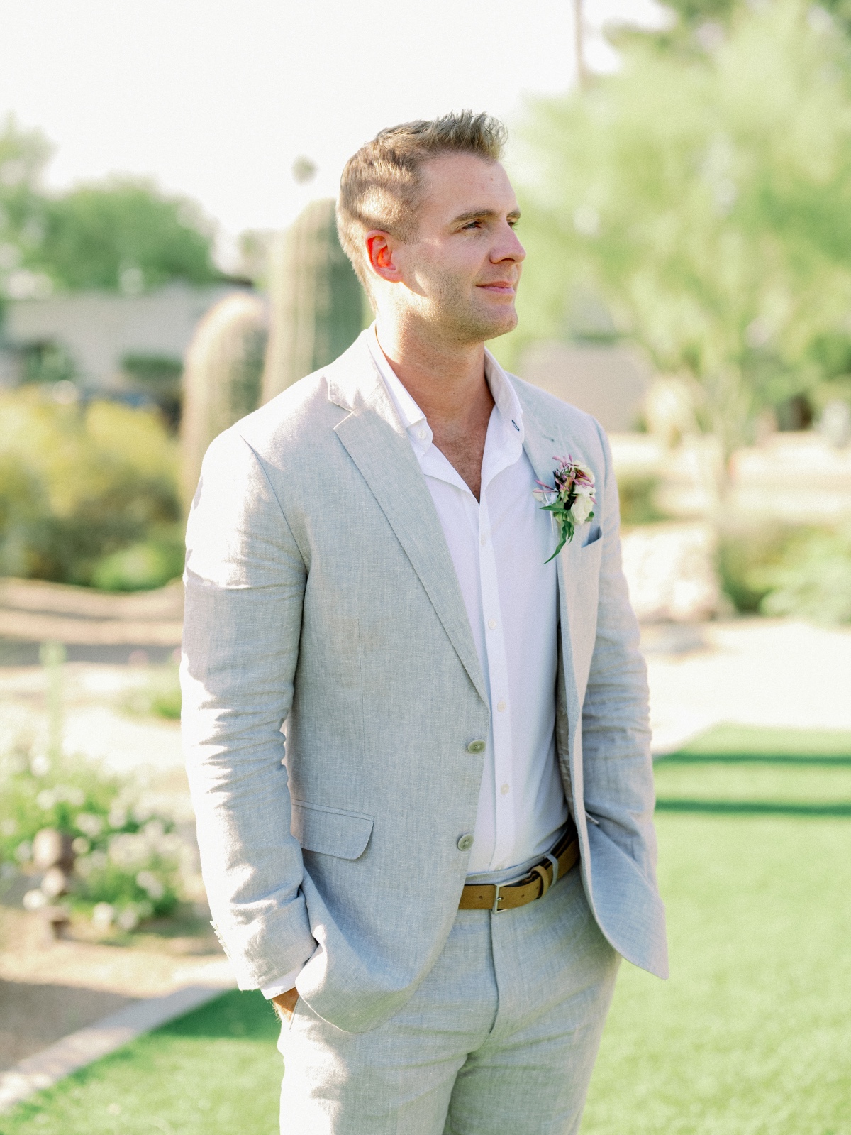 Modern groom in light grey suit at desert wedding venue 