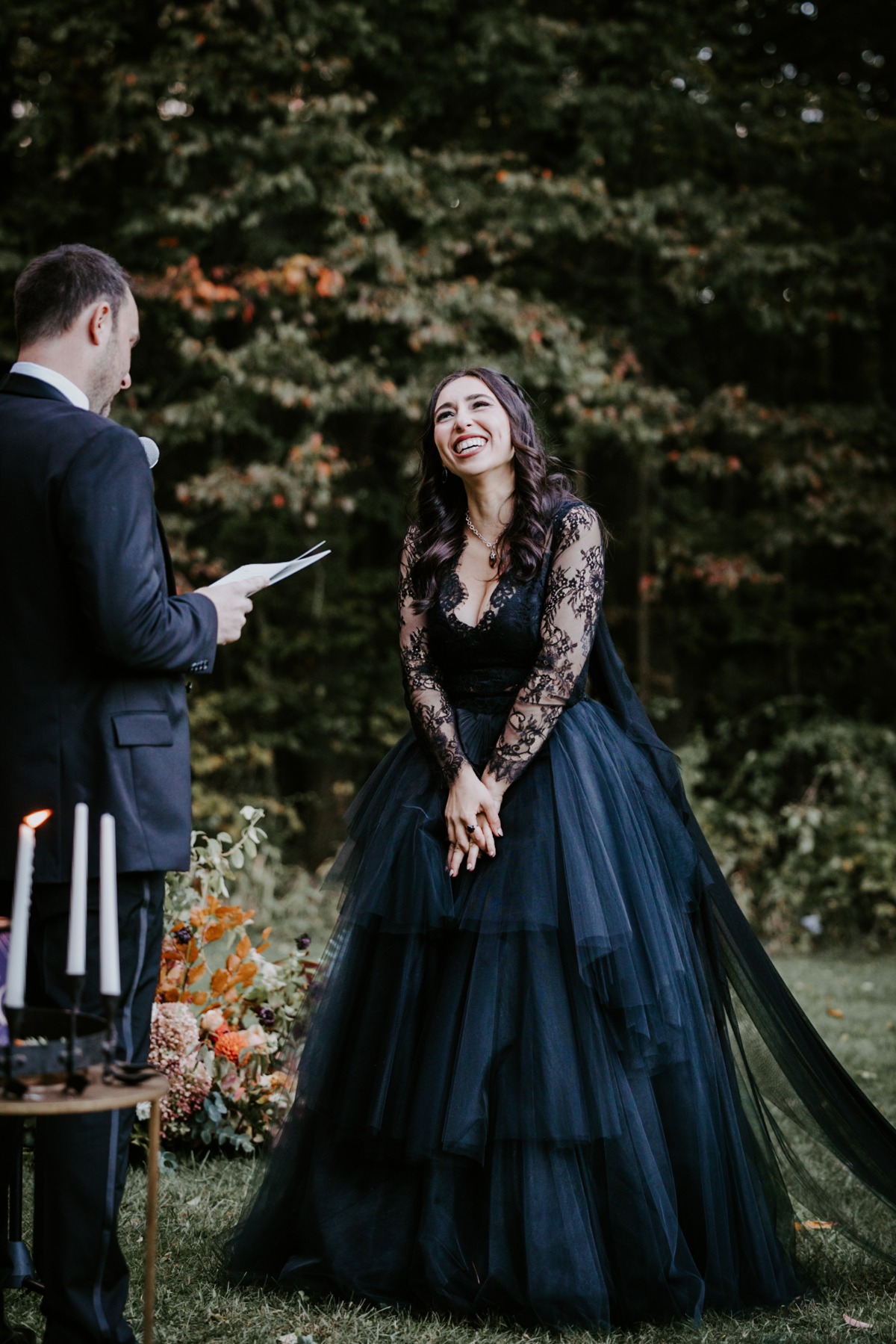 Laughing bride in black wedding dress at outdoor ceremony